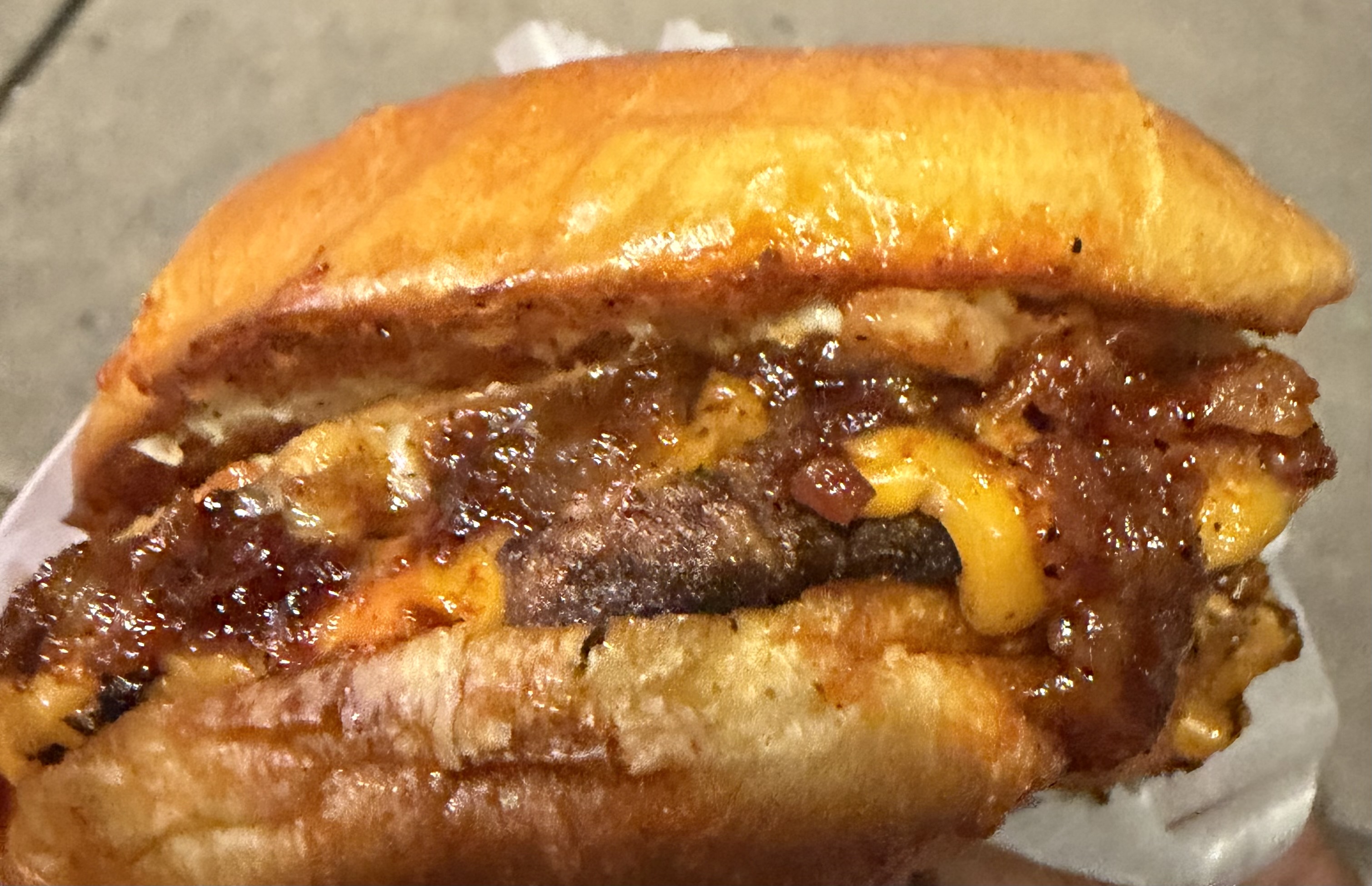 Cross-section of the Stash Burger Vault Burger — stacked charred patties, oozing cheddar and caramelized glaze on a toasted bun